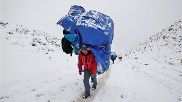 ポーターはエベレストのベース キャンプの方の大きい負荷と歩く